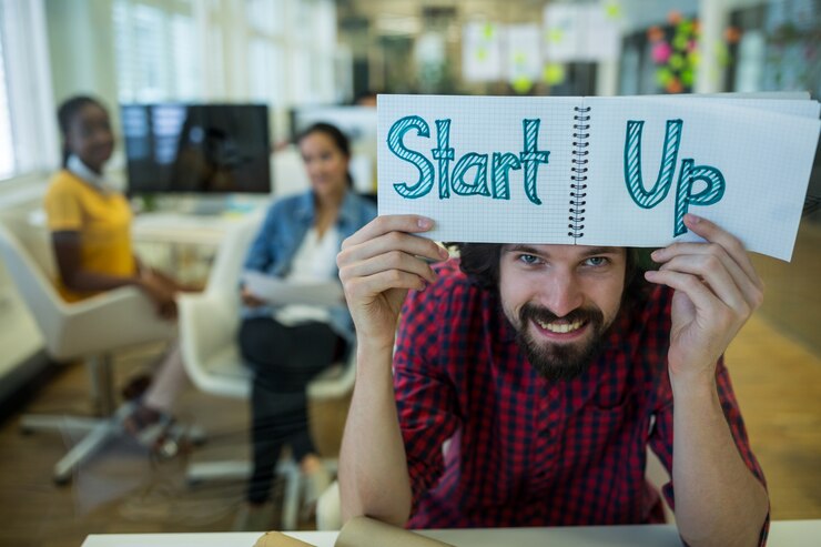 Male graphic designer holding spiral notepad with text - startup